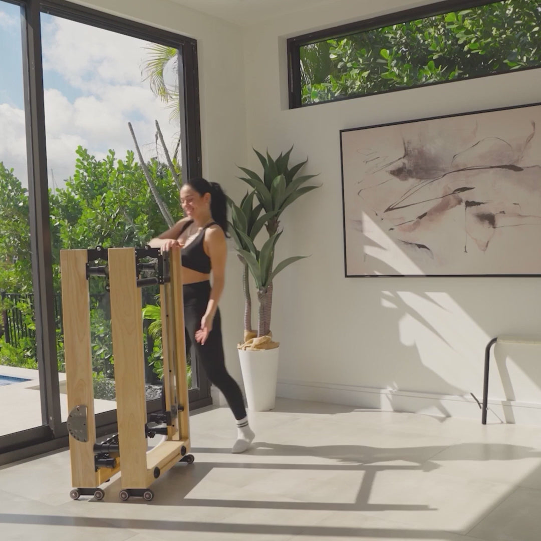 Load video: A maple foldable reformer being unfolded from storage, set up and used at home